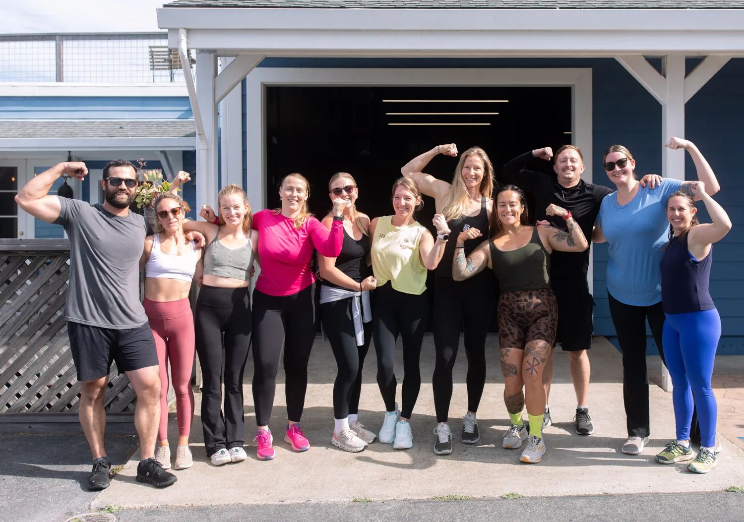 A group of Cove members flexing and smiling together outside the gym after class.